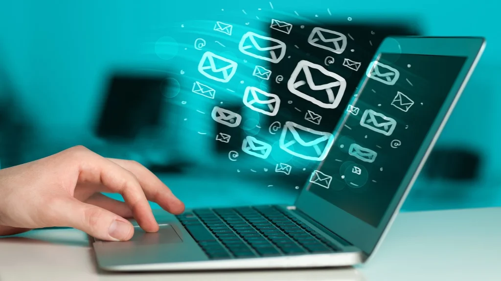 Hand working on a laptop that is receiving multiple email communications.