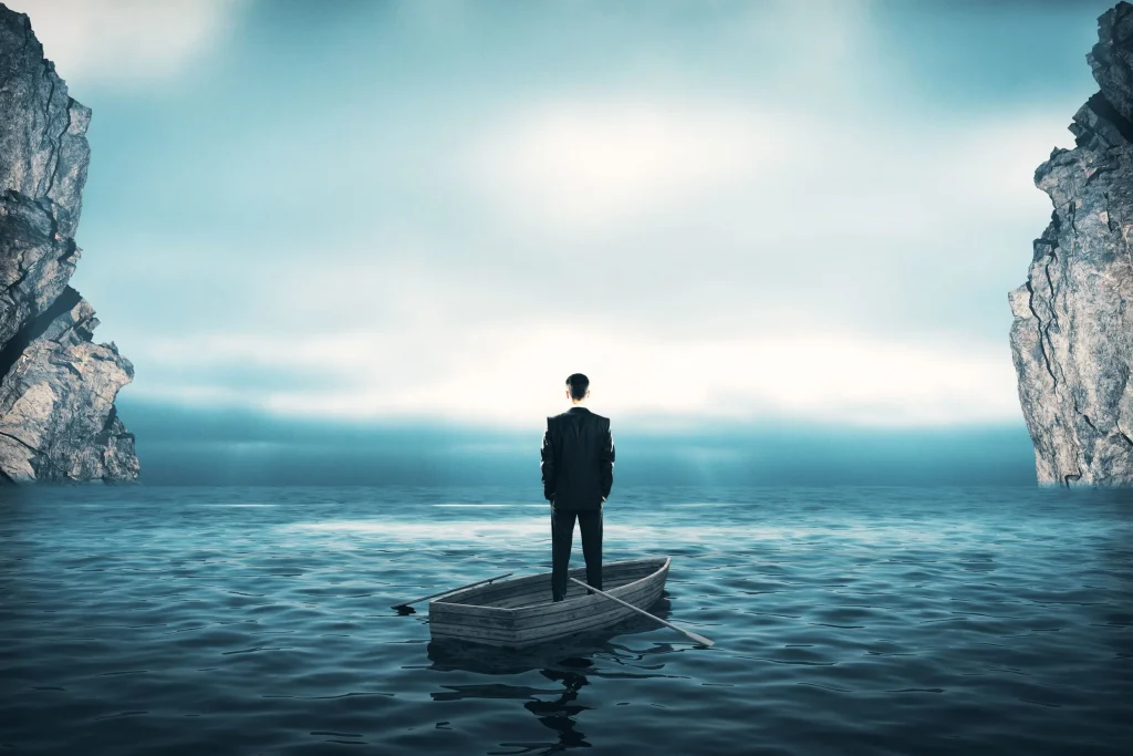 Man in a boat looking out to sea, symbolizing an unemployed, underemployed, or miserably employed person when faced with a career transition.