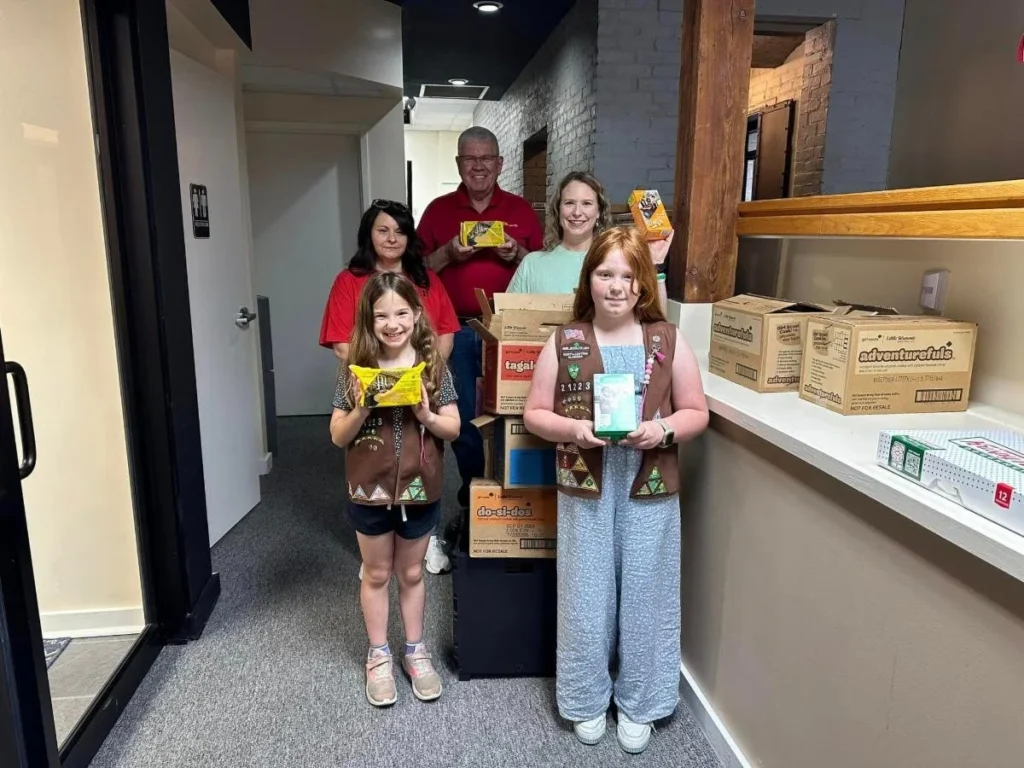 Happy family showing donated Girl Scout cookies to the camera.