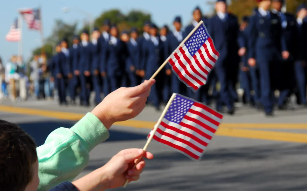 Kids waving American flags during a Veterans Day parade.