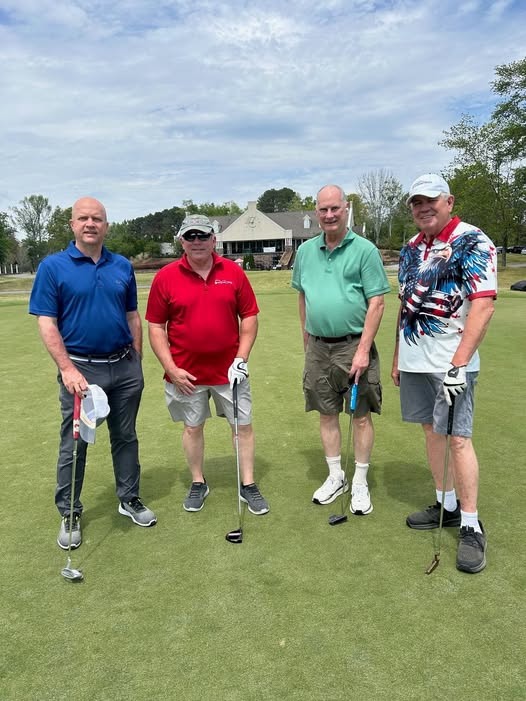 SSV members at a veteran golf event standing on a putting green with clubs.